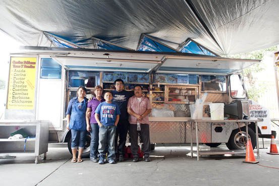 A family stands in front of a taco truck
