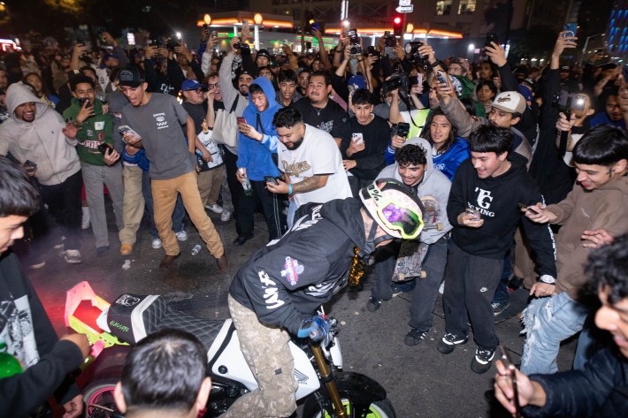A crowd watches a man on a motorized bike