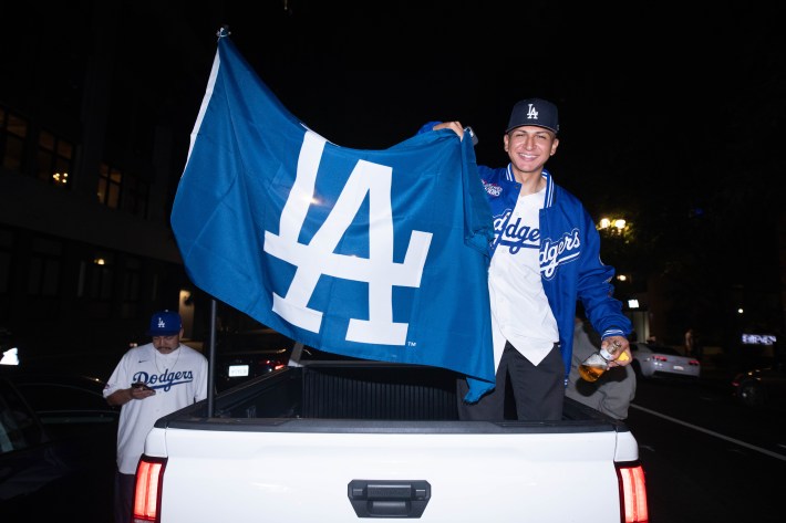 A man holds an LA flag from within a truck bed