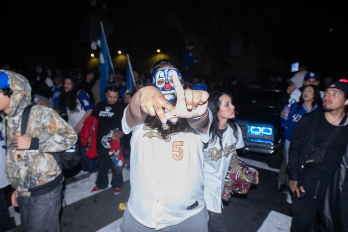 A man in face paint creates the LA logo with his hands