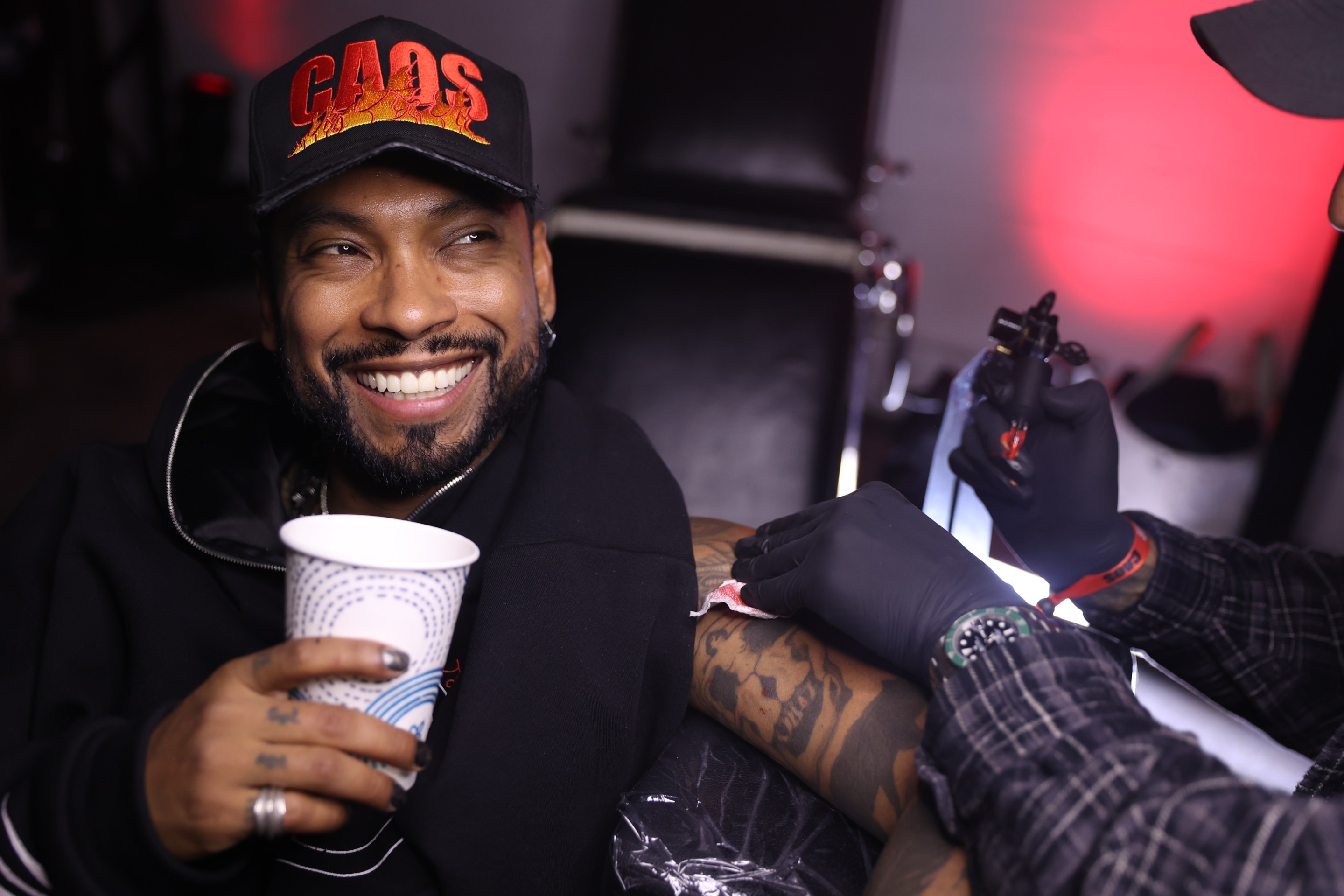 a man wearing a hat smiles as he is tattooed