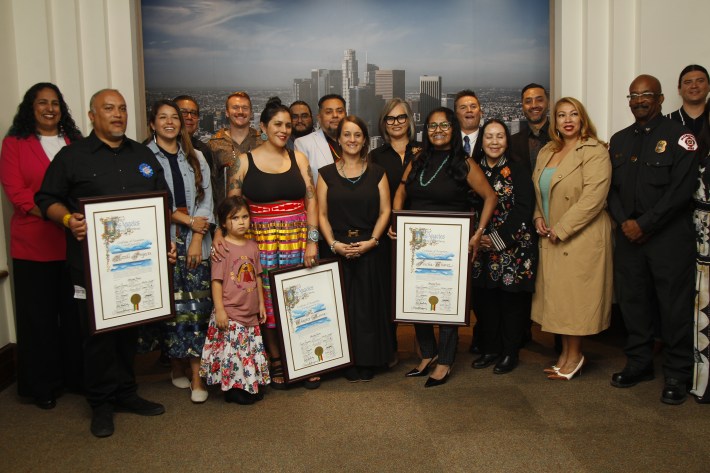 a group of people smiling and holding framed documents