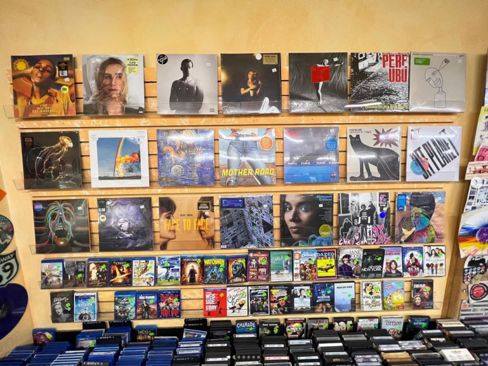 a wall of vinyl record covers. packaged CDs are being sold below