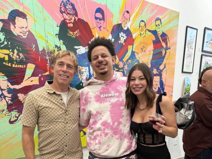 two men and one woman pose and smile together