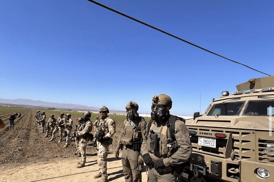 Masked federal troops in front of a vehicle