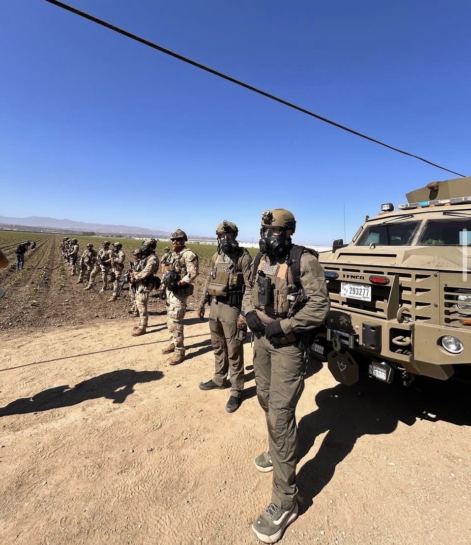 Masked federal troops in front of a vehicle