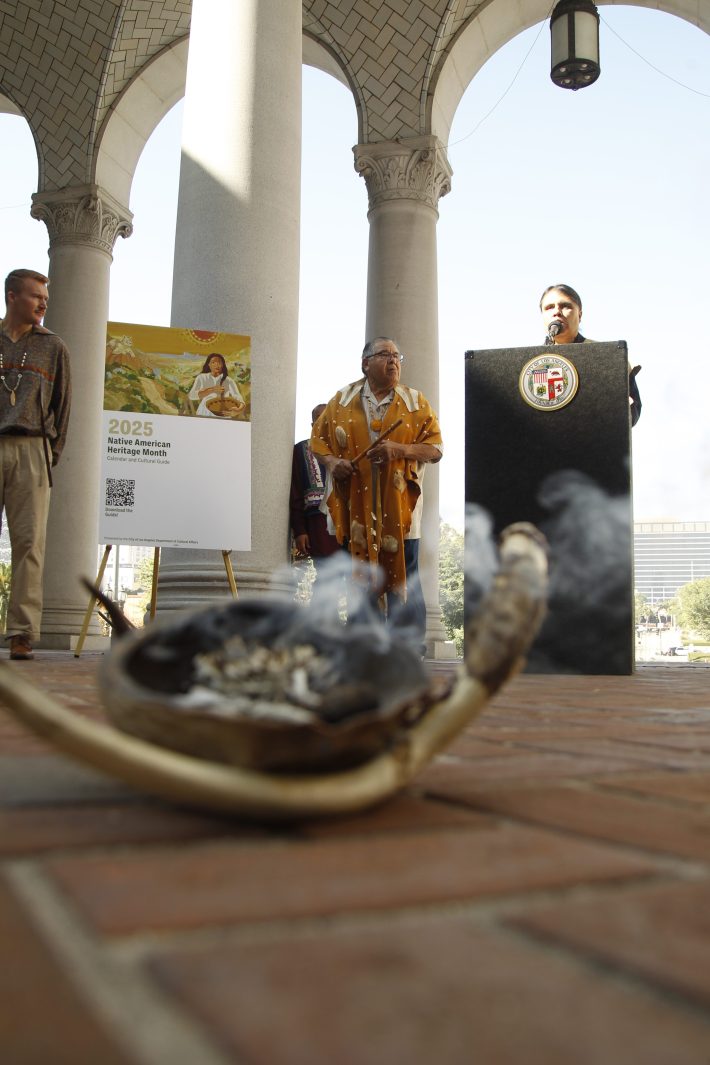 a ceremony takes place, two individuals looking at the person speaking from behind a podium