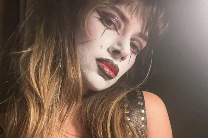 a woman in clown makeup looks suggestively into the camera