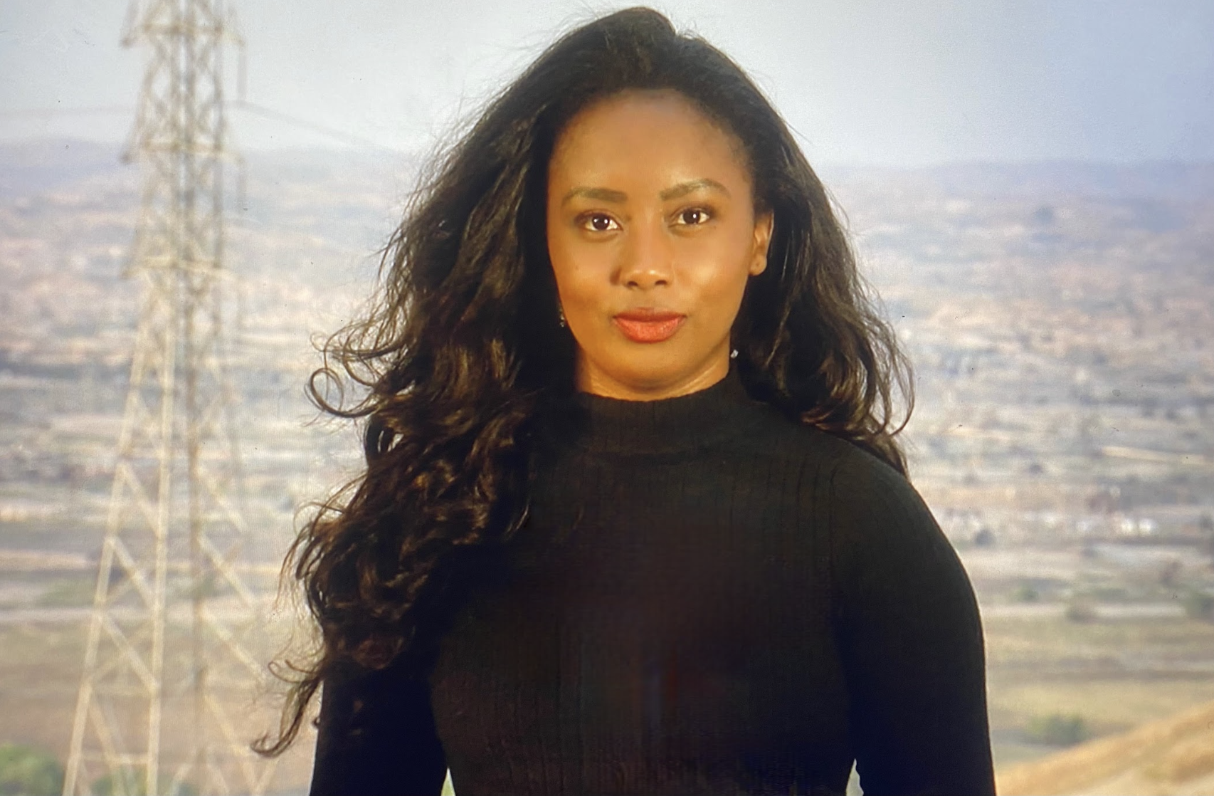 a woman stands in front of an image of a desert field