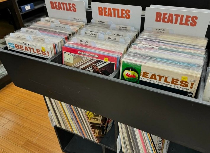three rows of Beatles records are on display at a record shop
