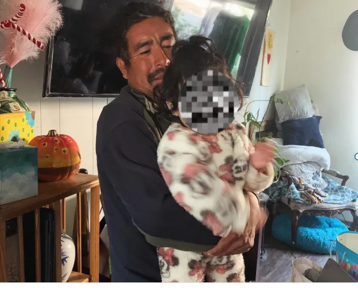 a man holds a little girl in a fleece onesie