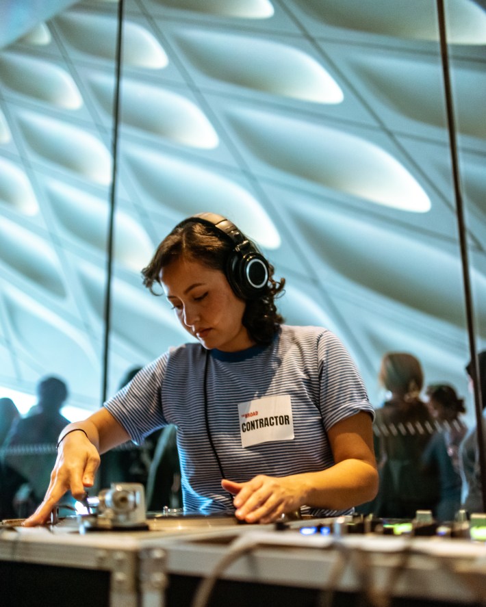 a woman with a pair of headphones mixes at a DJ set