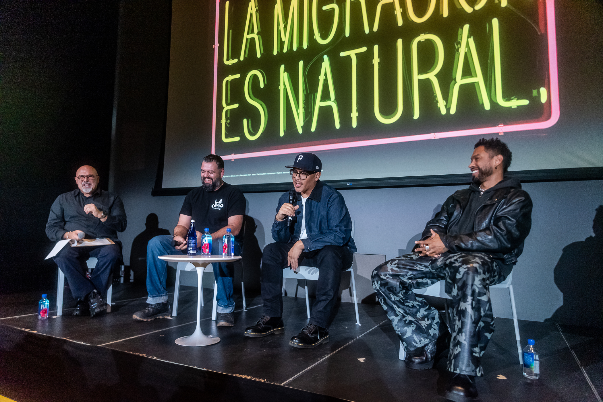 four men sit on a stage
