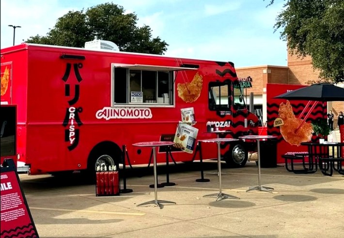 A red food truck with the word Ajinomoto on the side, selling gyoza dumplings in an outdoor area