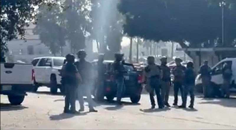 Several federal agents in masks and tactical gear stand in a parking lot