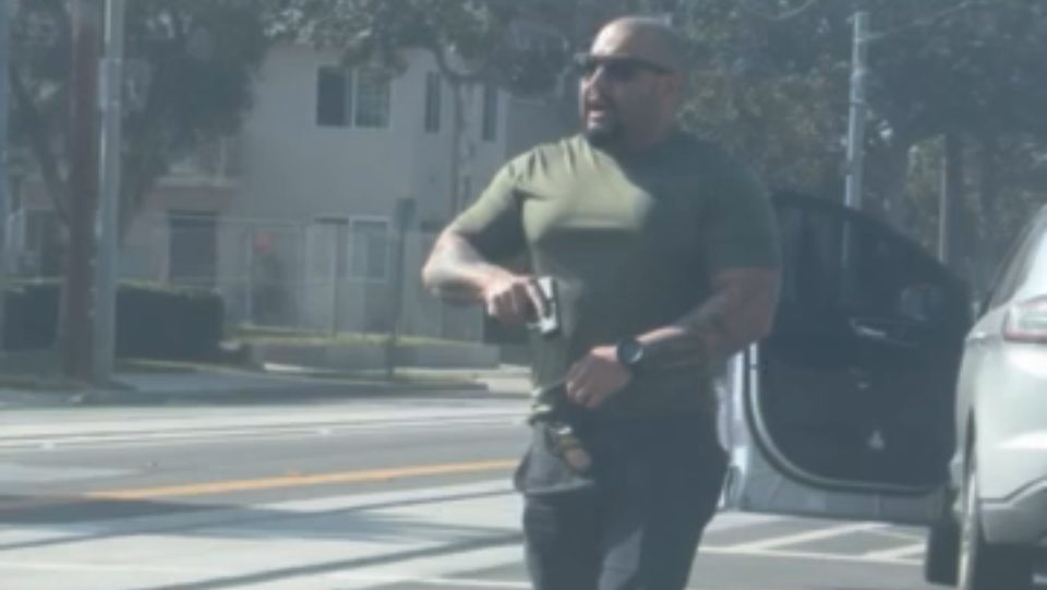 Federal officer brandishing weapon at Santa Ana community member. Photo courtesy of Sol.