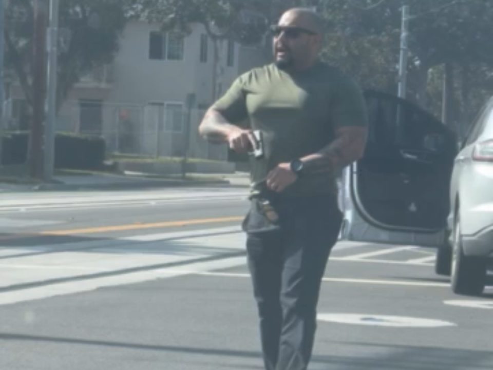 Federal officer brandishing weapon at Santa Ana community member. Photo courtesy of Sol.