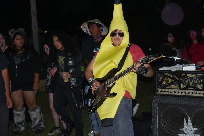 a young man dressed as a banana plays bass