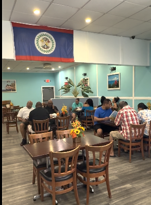 the interior of a small restaurant. there is a Belizean flag hanging