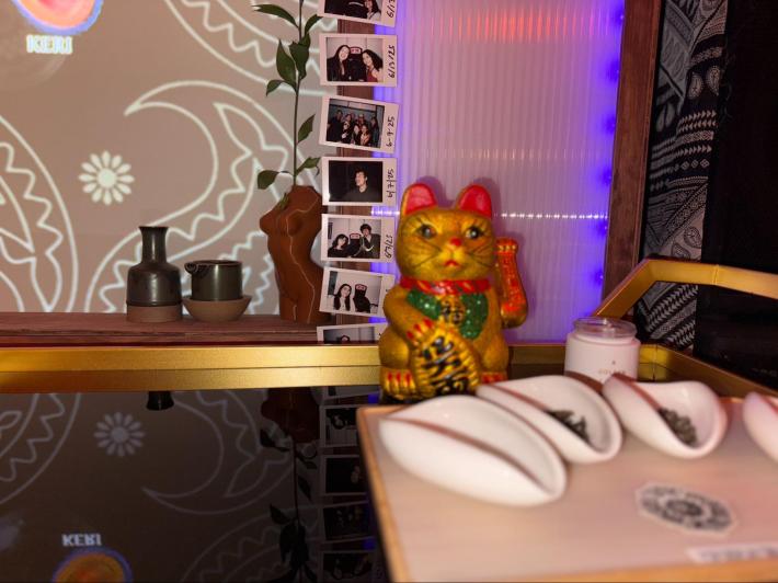 a Lucky Cat is on display in front of polaroids of people