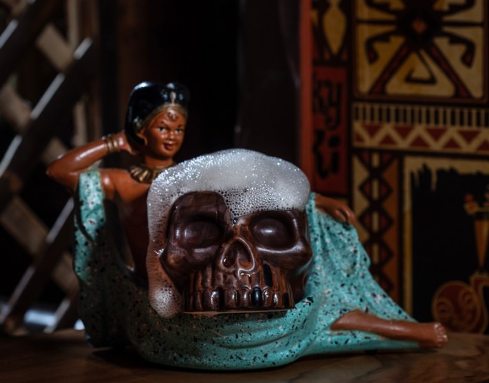 A skull-shaped cup with blue foam coming from the top at a tiki bar