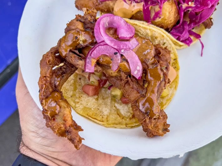 a softshell crab taco with pickled onions on top