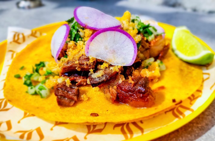 a taco with suadero, veggies, and chicharrón