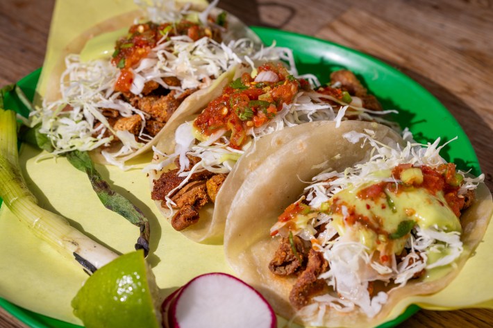 tripa tacos with cabbage and salsas on a bold green plate