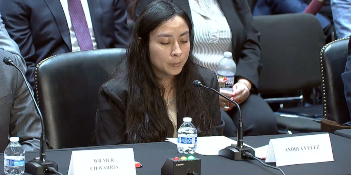 a woman in front of a microphone on a desk while at a court hearing