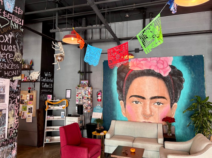 inside of a coffee shop. there is a large artwork of Frida Kahlo and comfy seating