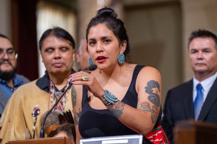 a woman speaks from a microphone attached to a podium