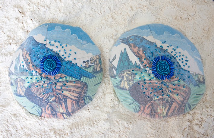 two sculptures depicting breast implants, sewn together with fabric and beaded