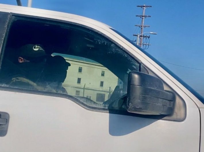 a sideview of a white truck being driven by a federal immigration agent