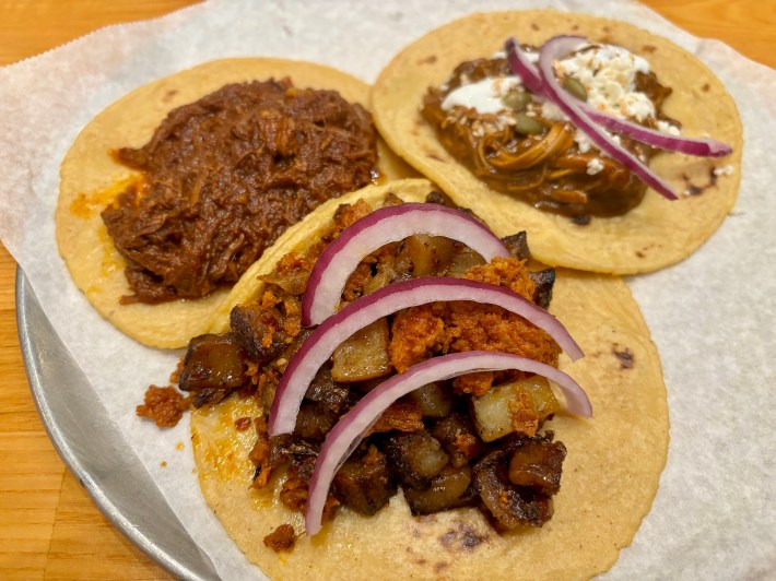 three meat tacos on corn tortillas on a serving platter