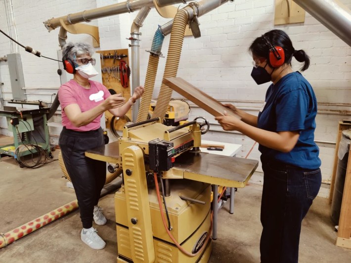 two women operate a woodworking machine together