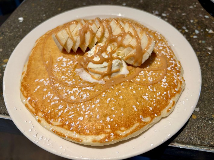 a pancake stack with toppings like bananas and drizzle