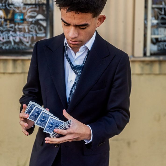 a young man in a suit shuffles cards