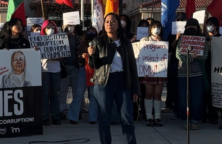 A woman holding a mic in front of rally goers.