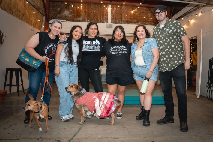 a group of people smile and pose together along with two dogs
