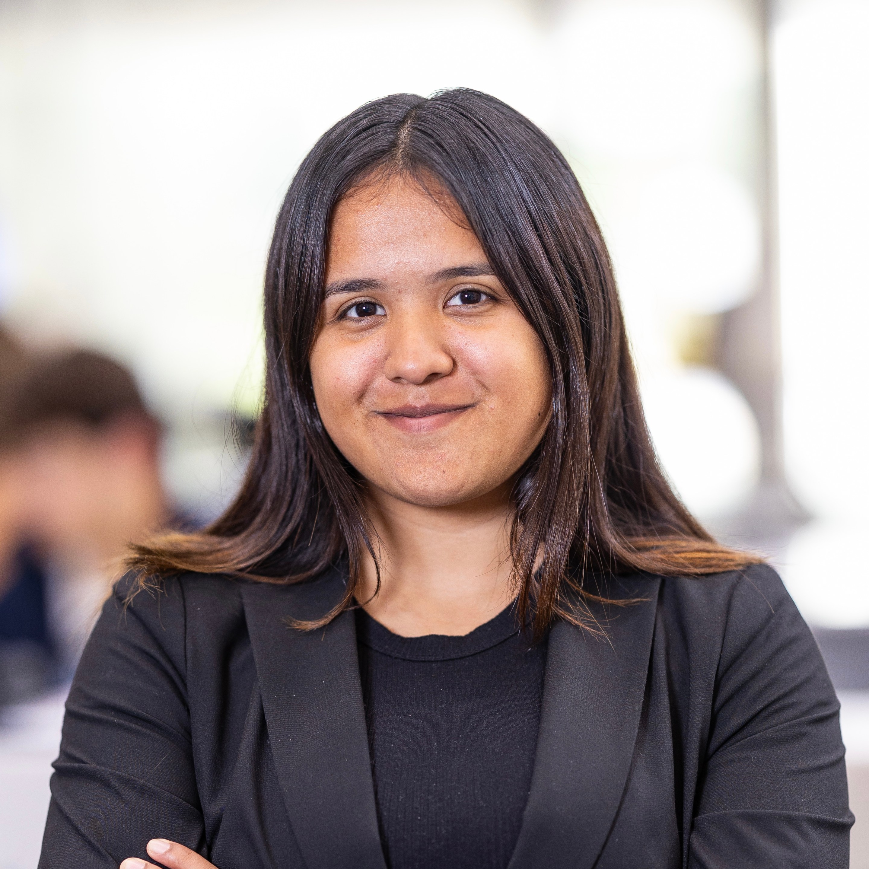 a young woman in a blazer smiles softly into the camera