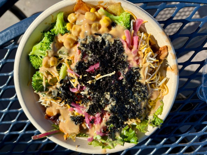 a Korean-inspired bowl of food including broccoli, seaweed, red onions, cheese, and pork