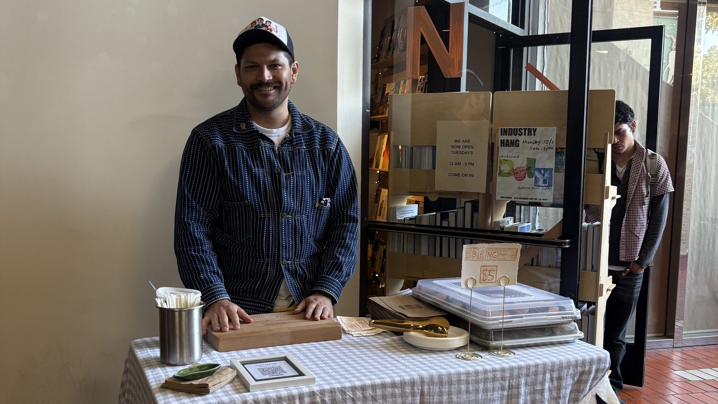 a man smiles at a table labeled "NANANUKA"