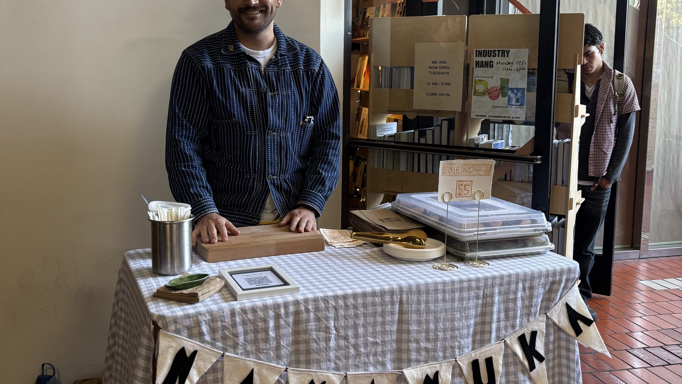 a man smiles at a table labeled "NANANUKA"