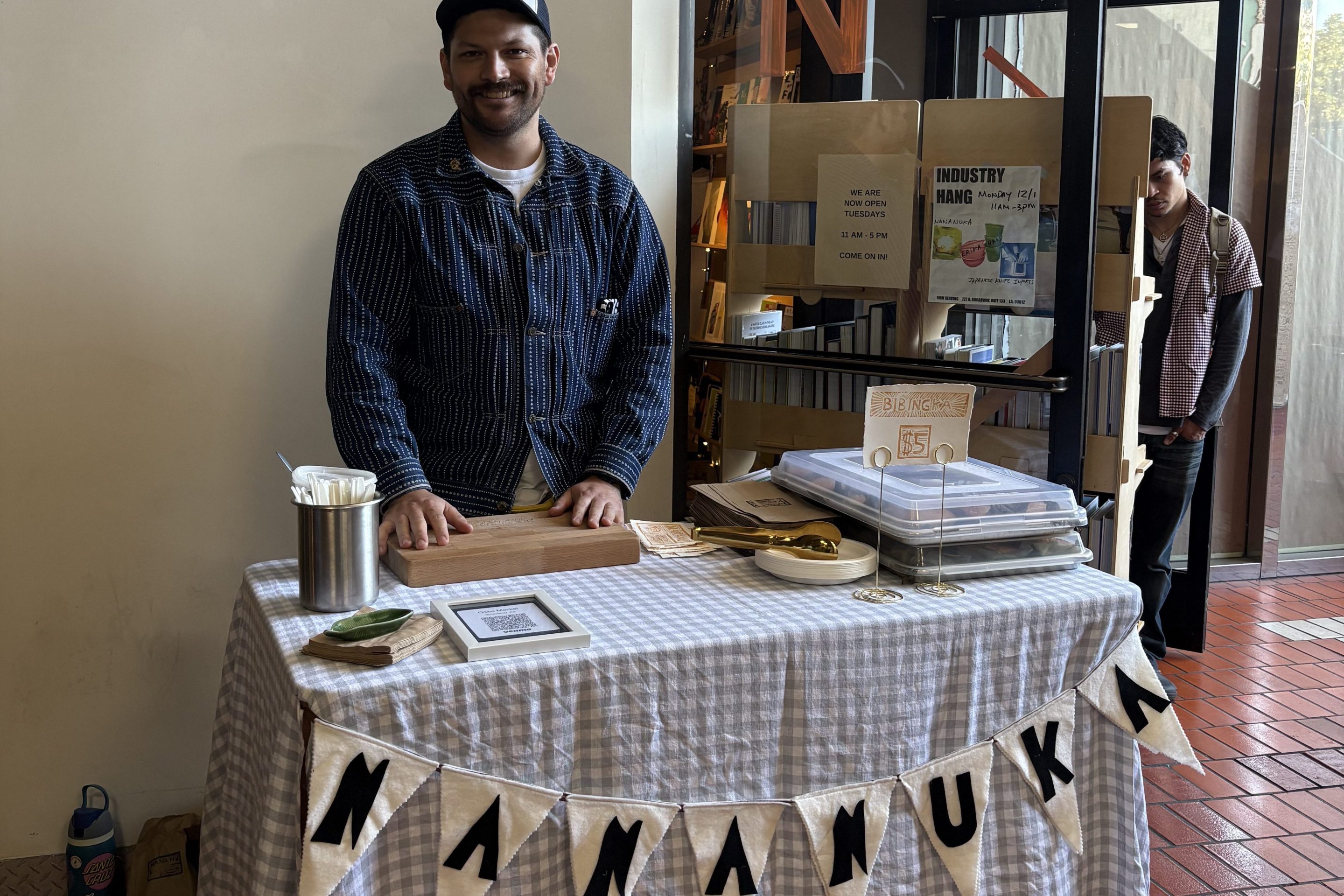 a man smiles at a table labeled "NANANUKA"