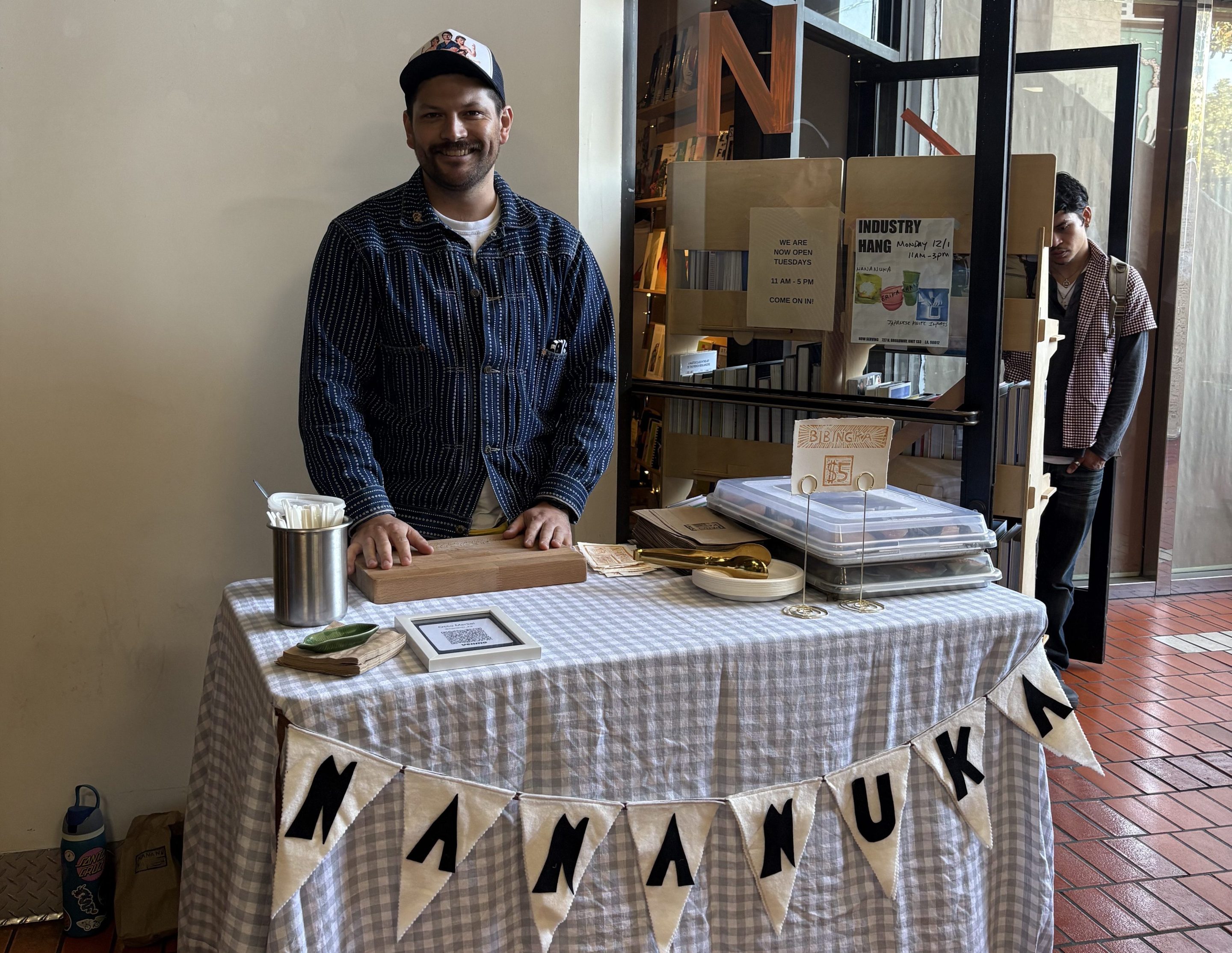 a man smiles at a table labeled "NANANUKA"