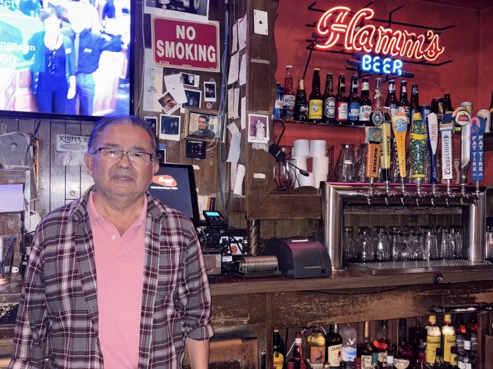 a bartender stands in front of a bar