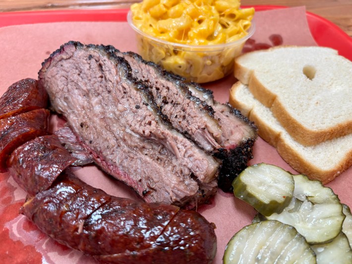 a bbq plate of jalapeno cheddar sausage, brisket, mac n cheese, pickles, and white bread