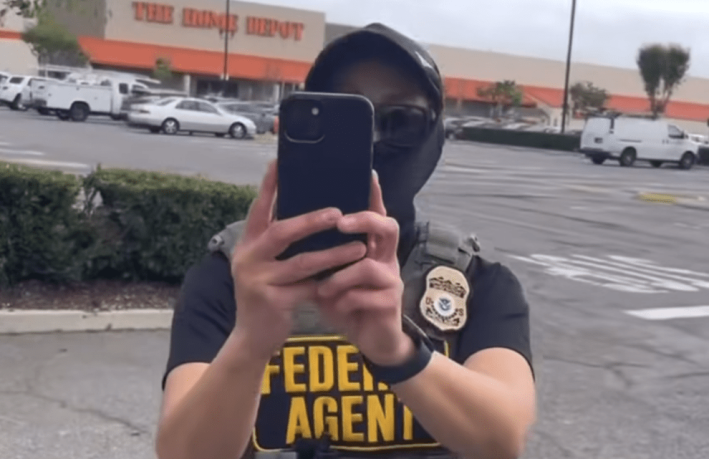 A “Federal Agent” holds their phone up to record a person recording them at the home depot parking lot in Playa Del Rey.