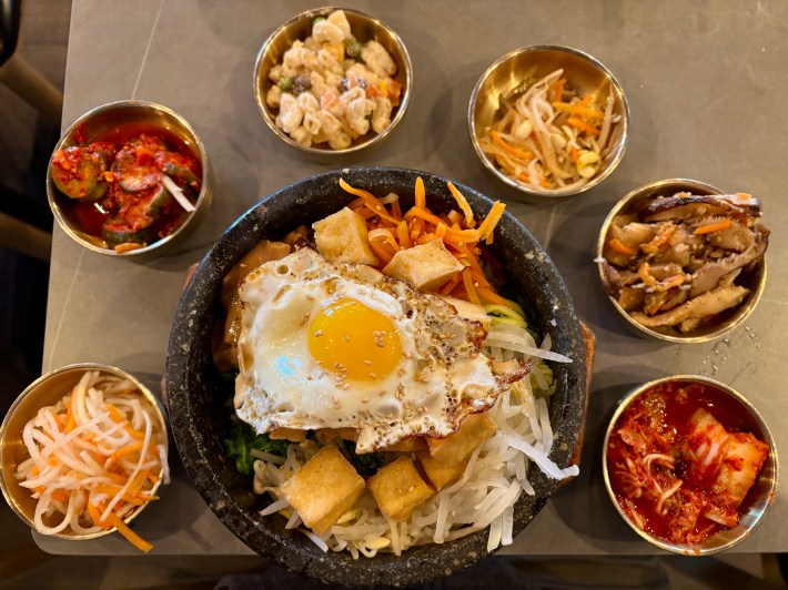 a bowl of bibimbamp along with smaller bowls of banchan
