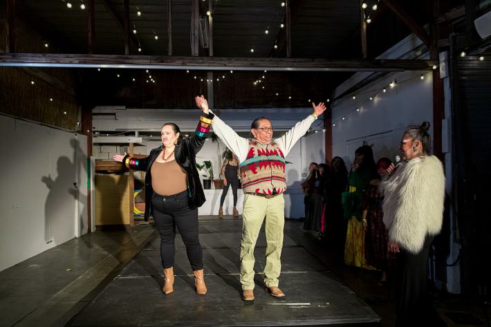 a woman in drag raises the hand of a man in a victorious manner while onstage
